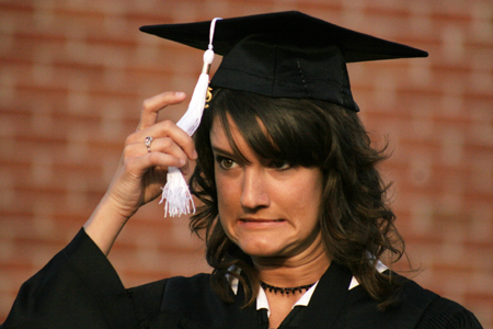 Spanish and TESL graduate Charli Cox almost forgets to move her tassle after receiving her degree at spring graduation.