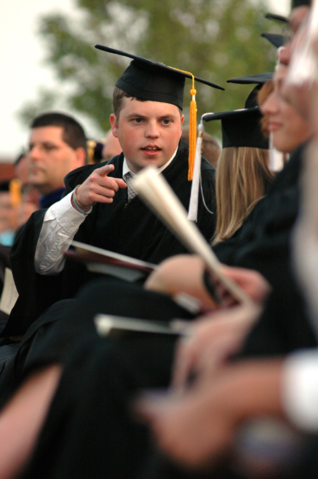 Senior class president Brandon Nelms speaks with those seated next to him during spring graduation.