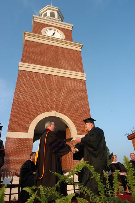 President Dockery presents Matt Oshell with a degree in political science at the spring graduation ceremony.
