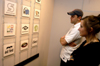 Enrollment Counselors Joe Garner and Lisa Whiffen examine Adam Houston's logo design during his senior graphic design show in the Art Gallery. - Photo by Jonathan Blair
