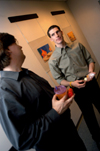 DMS Coordinator Chris Blair talks with Senior DMS major Adam Houston during his senior graphic design show in the Art Gallery.  Adam was the first DMS major to do a gallery show in addition to his senior seminar project. - Photo by Jonathan Blair