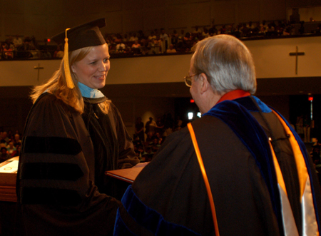 An education graduate accepts her diploma from President Dockery during summer graduation.