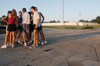 The cross country teams gather together for a quick prayer in the parking lot as the sun rises following the teams second early-moring practice of the season. - Photo by Brad Moore