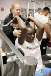 Assistant Coach Katie Woodruff (back) helps junior transfer D.J. Sissoko with her weight training. - Photo by Kyle Kurlick