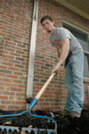 Junior Andy Robinette assists in the cleaning of a flower bed at the YMCA during the Day of Remembrance. - Photo by Brad Moore