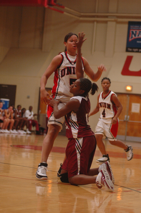 A Southern Nazarene player falls to the ground as she attempts to guard Union's Tiffany Fisher (14) while Jessica Graves (4) looks on.