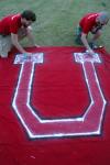 Ronald Long and Mike Evans prep the U flag with an extra coat of spray paint moments before the pep rally march from Miller Tower to the soccer fields. - Photo by Kyle Kurlick
