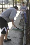 Freshman Alex Ayris helps Junior Brian Burns clean up the playground sidewalk at Alexander Magnet Elementary School during Day of Remembrance. - Photo by Stephanie Schroeder