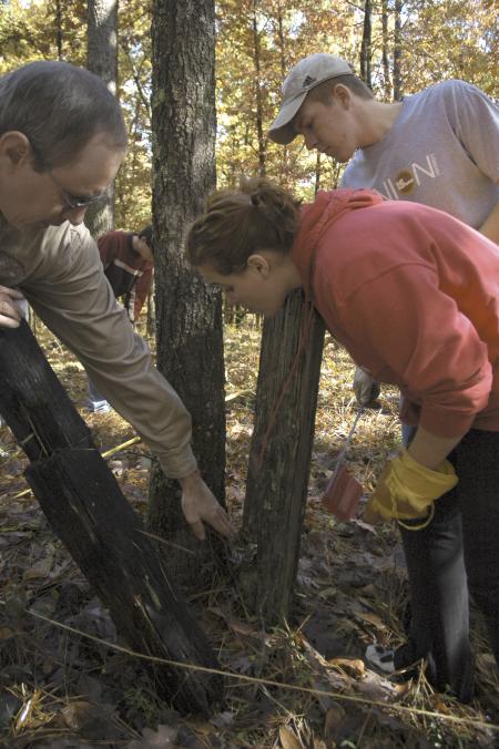 Jamie Evans, the cultural resource manager of the Ames Plantation, points out fence posts that pre-date the Civil War in a graveyard on the plantation to Senior History Majors Cassie Harris and John Crawford during the Day of Remembrance.