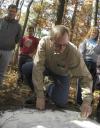 Jamie Evans, the cultural resource manager of the Ames Plantation, demonstrates how to read a grave stone using flour, as David Thomas, professor of history; Josh Abbotoy, English major; and Rachel Campbell, history major; observe during a Day of Remembrance project.  - Photo by Matthew Diggs