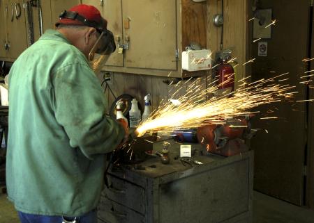 Danny Scott assists the grounds crew by keeping the lawn mower blades sharp so the mowers will cut the grass smoothly. 