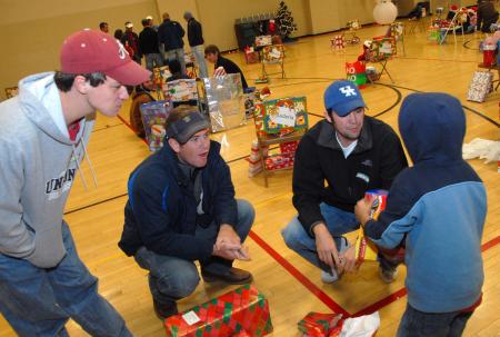 Jeff Norris, Brett Jenkins and Micah Whitaker watch as their child opens his presents during the SAC Carl Perkins' Christmas Party.