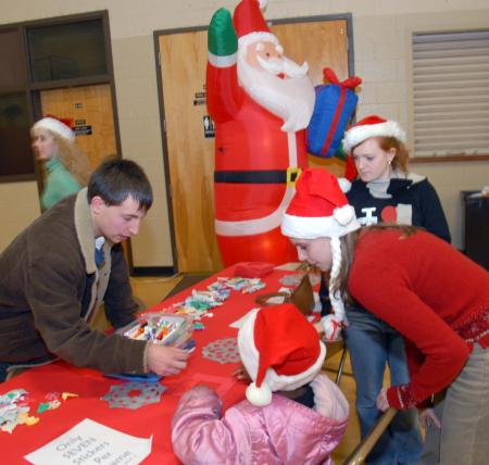 Cam Armstrong, Emily Watlington and Kinsey Bolinger color with one of the children during the SAC Carl Perkins' Christmas Party.