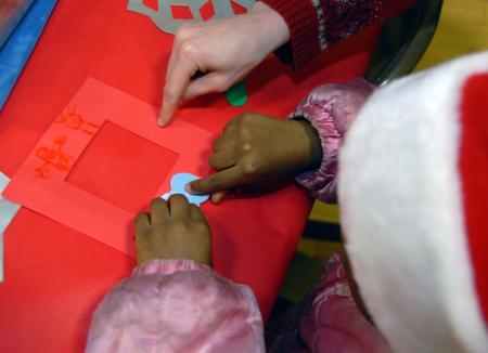 Emily Watlington helps a child with a crafts project during the SAC Carl Perkins' Christmas Party.