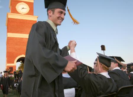 Tyler Porter and Clay Manley high-five each other after receiving their diplomas.