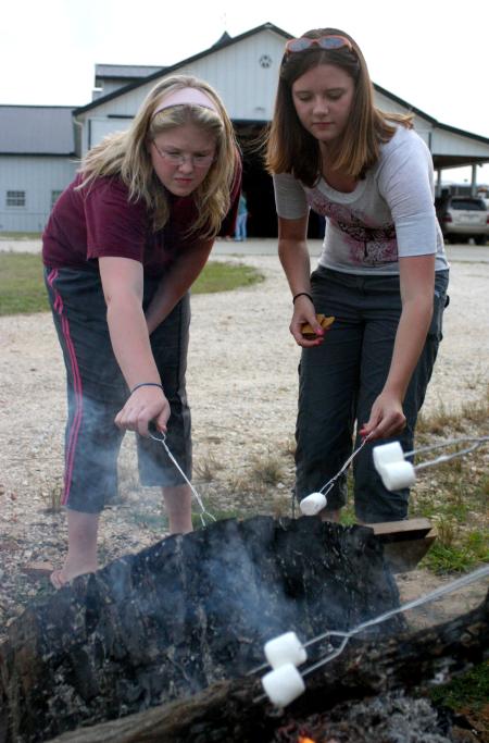 Rising Seniors Victoria Allen and Jessica Pikowski roast marshmallows and make s'mores during a cookout at the home of the Abshers.