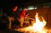 Sophomores Rebekah Frost and Paige Ward throw more wood into a pit fire.  Ceramics students were firing their projects primitive style. - Photo by Stephanie Schroeder