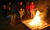 Sophomores Rebekah Frost and Paige Ward throw more wood into a pit fire as Lee Benson, professor of art, and other students watch. Ceramics students were firing their projects primitive style. - Photo by Stephanie Schroeder