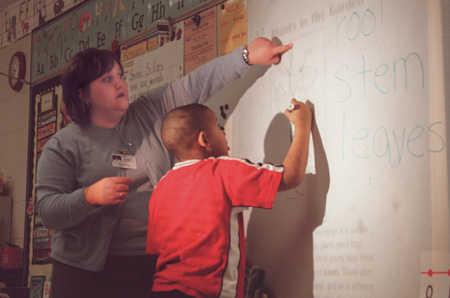 Assignment: Alison Oshel/Student Teacher - During science class, the first graders learned about plants. Tremayne Floyd draws the stem of the plant on the board under Oshel’s direction.