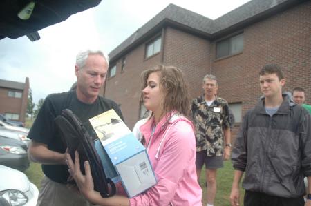 Sophomore Nursing major Ashley Burdenette helps unload a trunk full of freshmen belongings.  