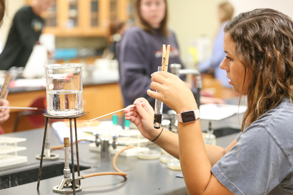 student with beaker in White Hall