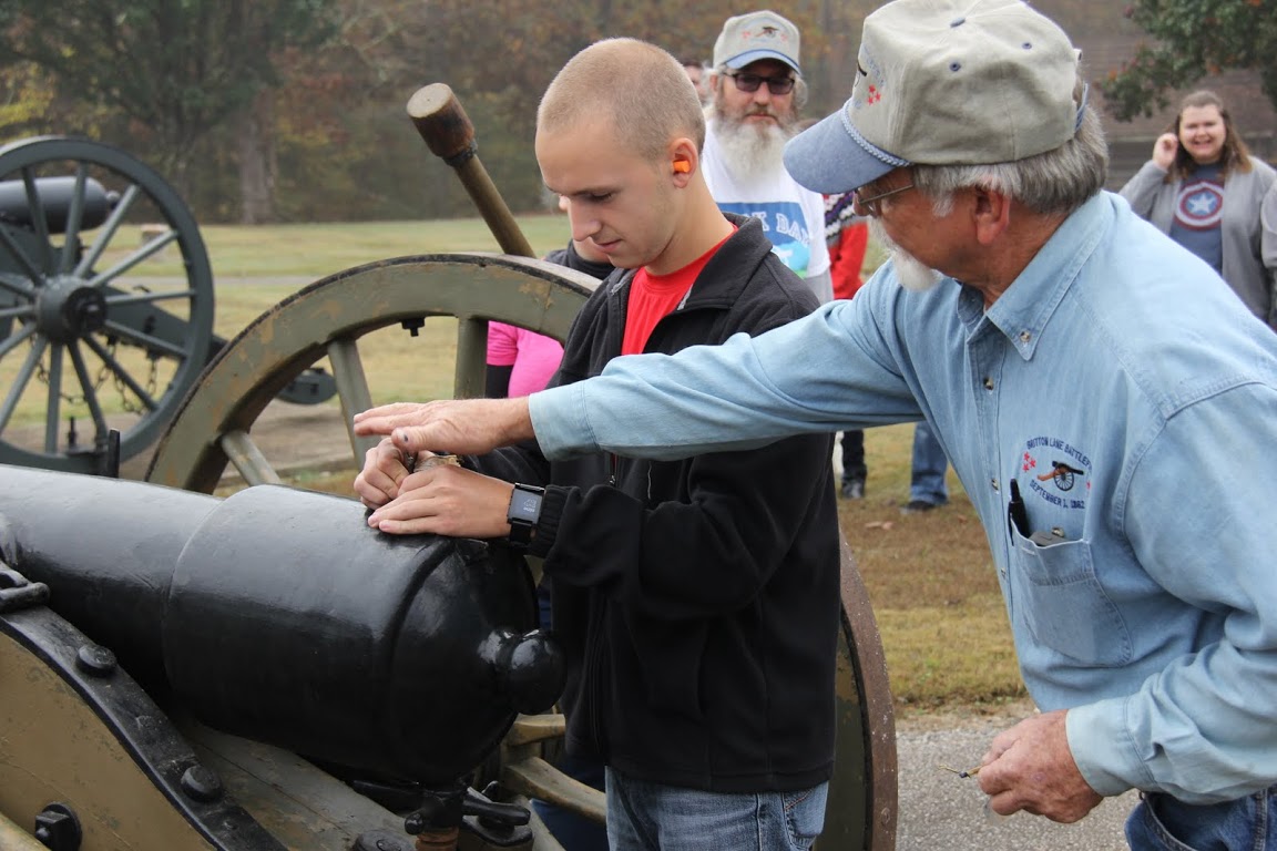 Britton Lane Battlefield Association President Jim Weaver helps Devin Dean use the priming wire to prepare a cannon for firing at the history department's Day of Remembrance activity at Britton's Lane on November 3, 2015.