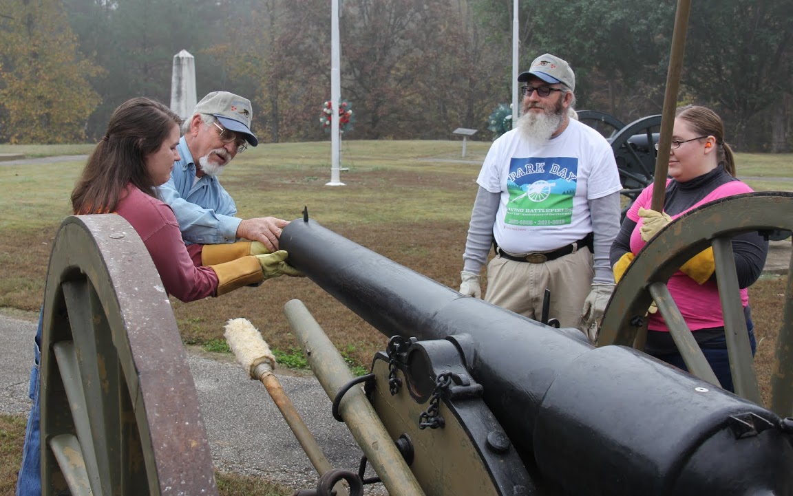 Britton Lane Battlefield Association President Jim Weaver (second from left) assists Phi Alpha Theta member Jordan Sellers (left) in putting a packet of gunpowder in the barrel of a cannon on November 3, 2015. James Price (second from right) and Hannah Conway observe.