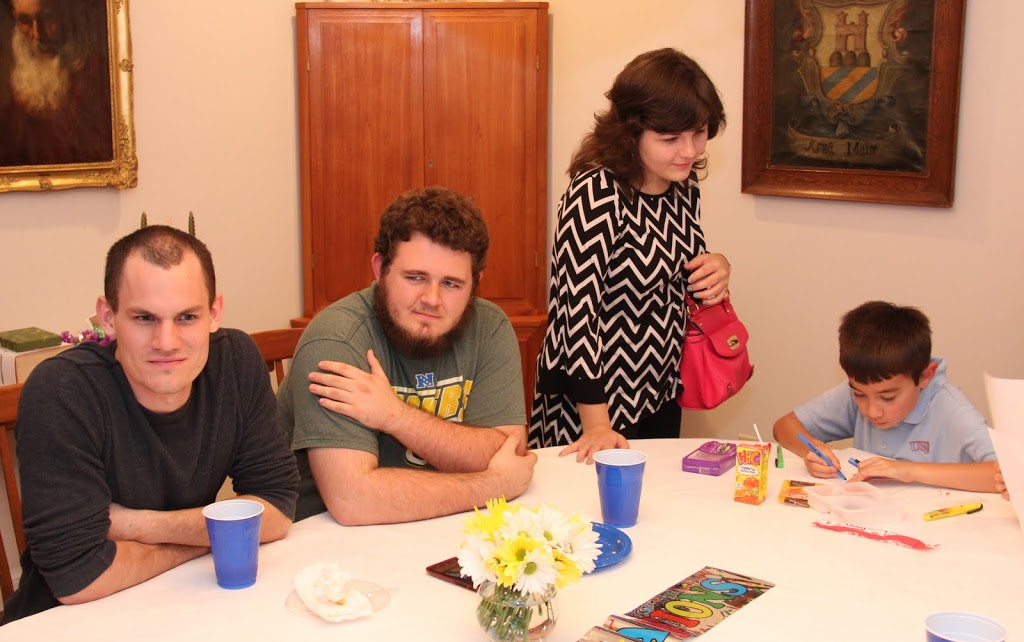 Pizza party attendees Jonmark Hetrick(left) and Nicholas Hancock participate in a table conversation, while Priscilla Porter (standing) admires the artistic talents of Matthew Allen on October 16, 2015.