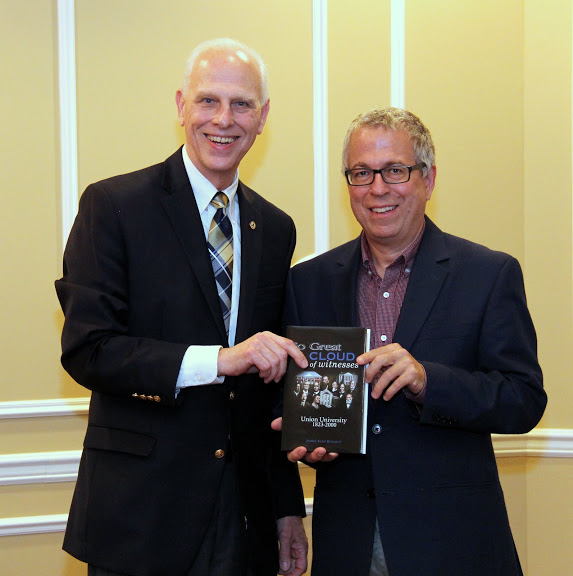 Dr. Stephen Carls (left) gives a copy of a book about the history of Union University to Dr. Robert Citino at a dinner in honor of the history lecturer on October 29, 2015.