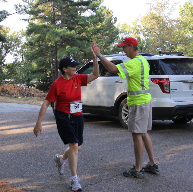 Dr. Alice-Catherine Carls, a competitor in the 5k race at the Racing So They Can Ride event on September 19, 2015, gets a high five from Phi Alpha Theta race volunteer Robert Briley.