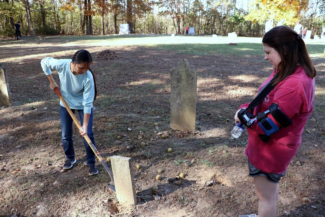 Kathryn Mitchell (right) watches Katherine Cheshire work on straightening a tombstone at Salem Cemetery on November 1, 2016. Photo by Elizabeth Wilson