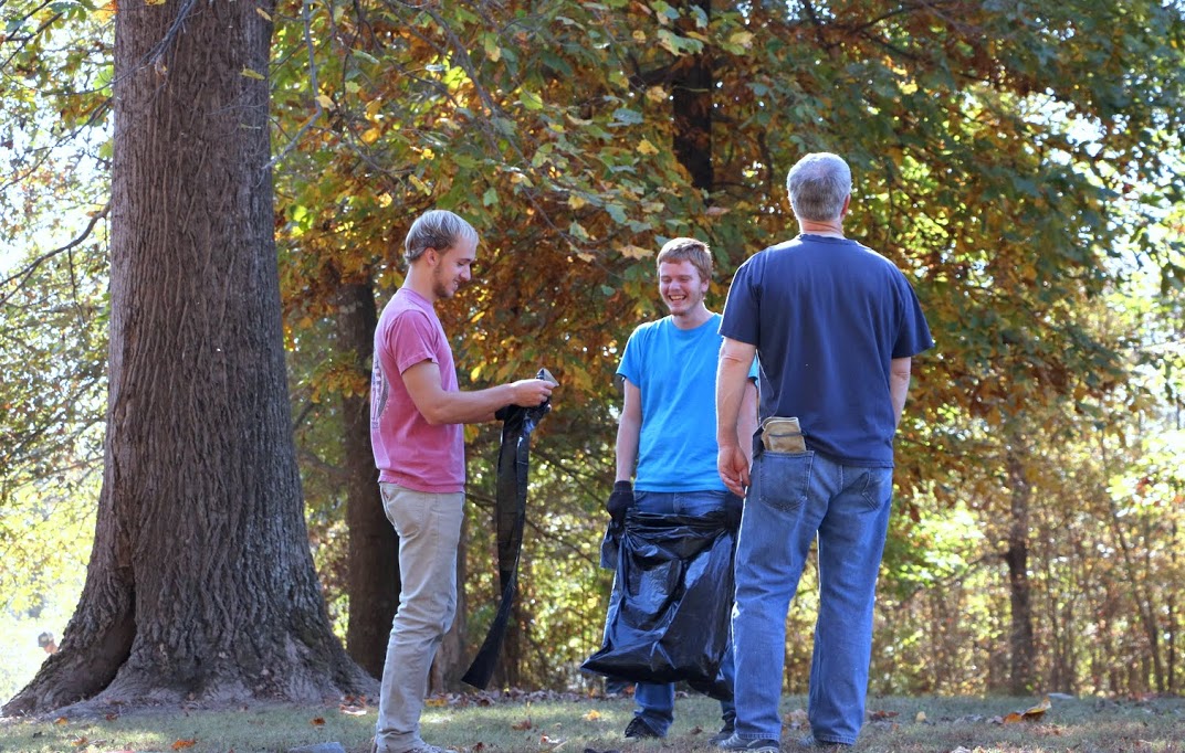 Devin Dean (left) and Gideon Ragland (center) smile as they help put leaves in plastic bags at Salem Cemetery on November 1, 2016, while Dr. David Thomas (back to camera) looks at the beauty of the cemetery's trees. Photo by Elizabeth Wilson