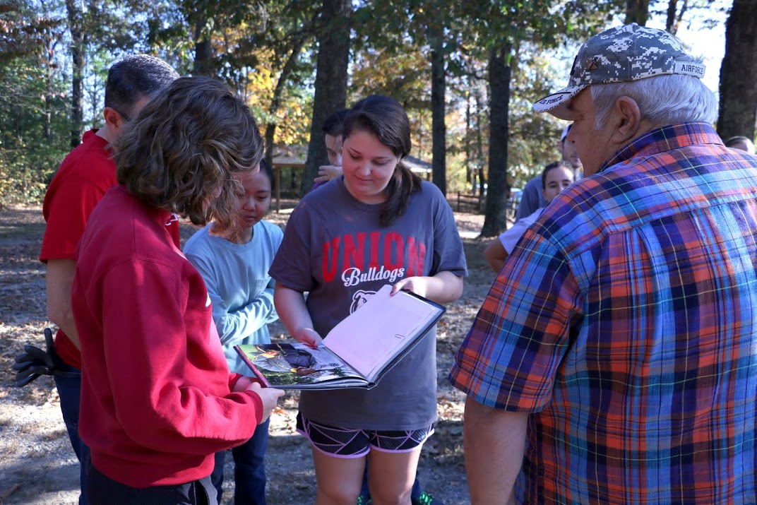 Malcom Wilcox (right) has Union community service project participants look at a photo of him in a book about the Civil War on November 1, 2016. Those looking at the photo are (starting at the left front and going clockwise) Beth Adams, Dr. Keith Bates (gloves in back pocket), Katherine Cheshire, and Emily Littleton. Photo by Elizabeth Wilson