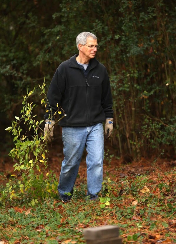 Dr. David Thomas carries a branch for loading onto a dump truck at the history department's community service project at Liberty Garden Park on November 7, 2017. Photo by Kristi Woody