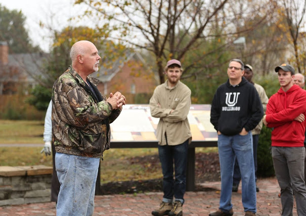 Dr. Kelvin Moore (left) leads the history department's Day of Remembrance group in a closing ceremony at Liberty Garden Park on November 7, 2017. In the background are Luke Sower (left to right), Dr. Keith Bates, and Seth Reid. Photo by Kristi Woody