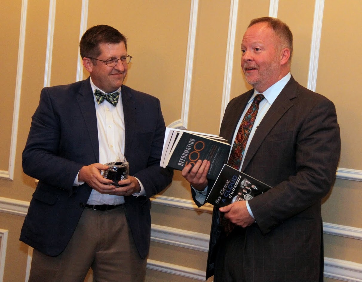 Dr. Ray Van Neste (left) of Union's School of Theology and Missions makes a presentation of books and a coffee mug to Dr. Bruce Gordon at the Carls-Schwerdfeger History Lectureship dinner in Gordon's honor on October 19, 2017.