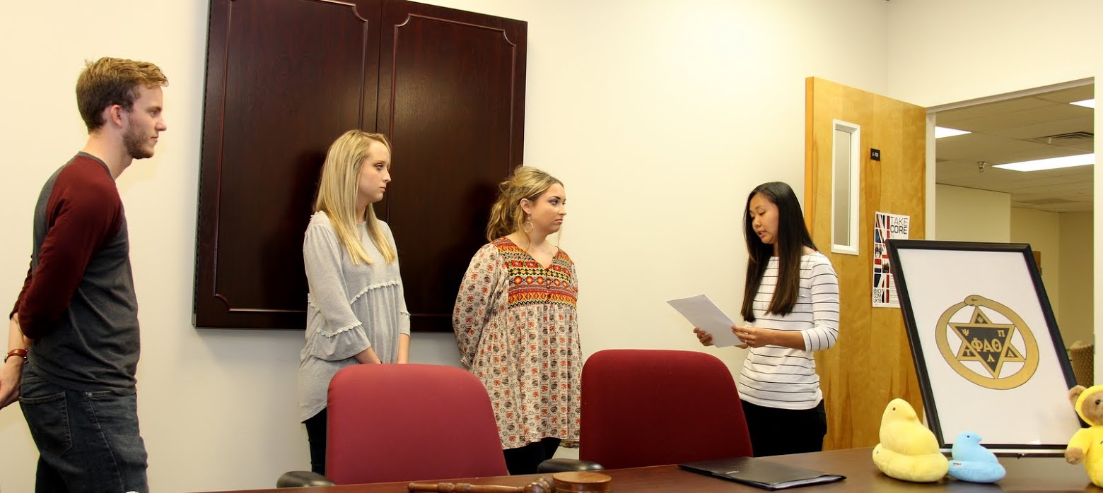 Delta-Psi Chapter Vice President Katherine Cheshire (right) conducts the Phi Alpha Theta induction ceremony for Nakota Wood (second from left) and Marylee Barker. Chapter President Seth Reid (left) observes.
