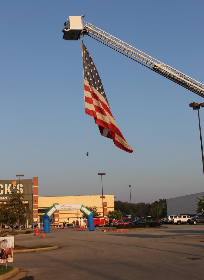 A large American flag suspended from a hook and ladder fire truck adds to the atmosphere at the Racing So They Can Ride event on September 16, 2017.