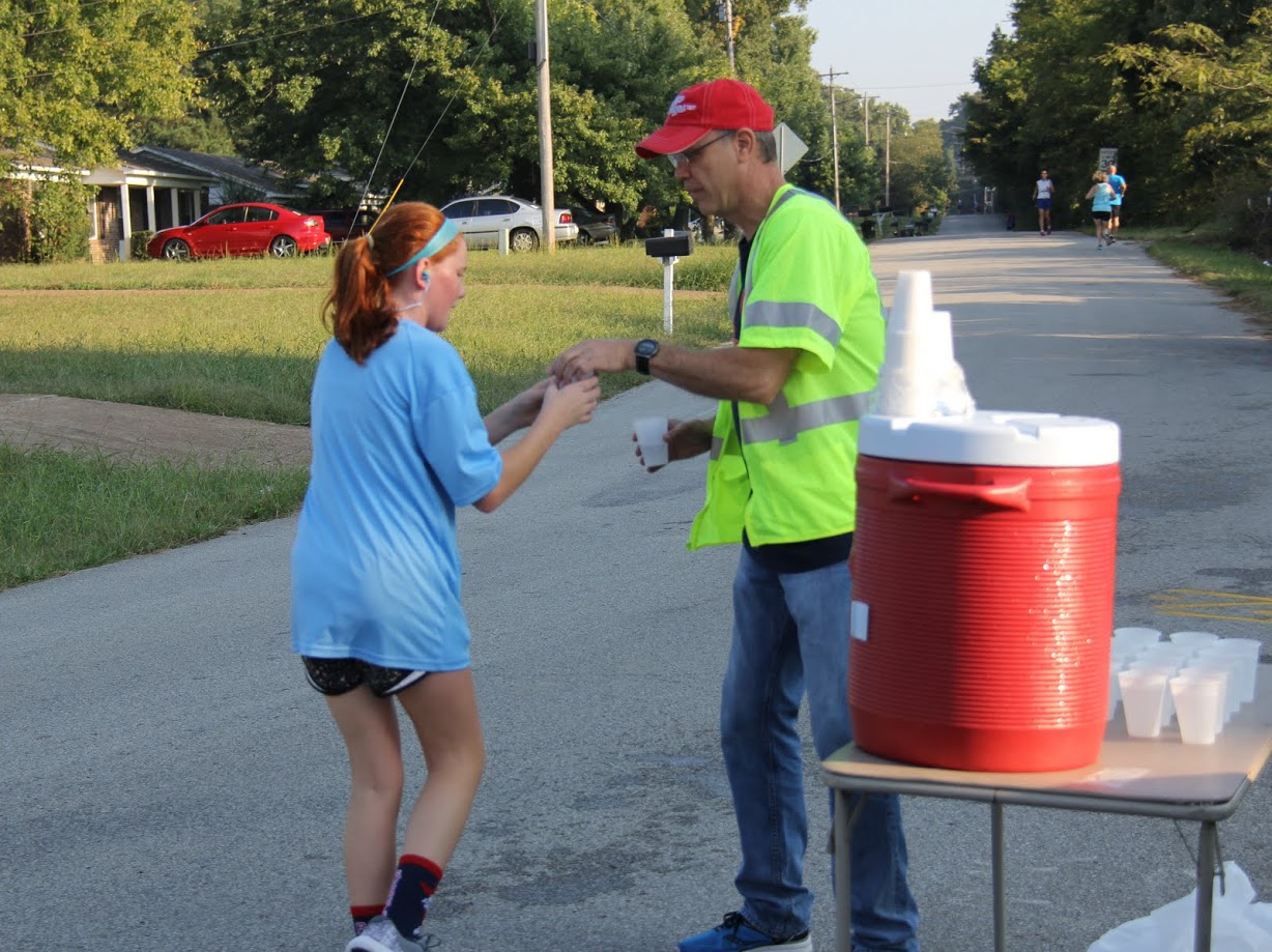 Robert Briley gives a glass of water to a runner at the Racing So They Can Ride races on September 16, 2017.