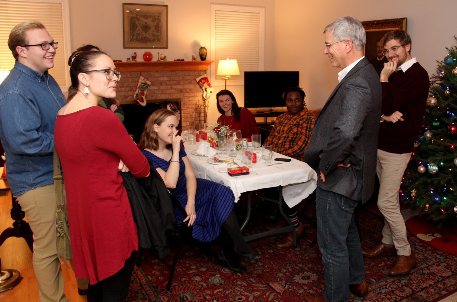 French Christmas dinner attendees listen Dr. David Thomas (second from right) tell a story toward the end of the evening on December 8, 2018. Those who are visible are (left to right) Nathan Heatherly, Katie Allison, Megan Ledbetter (seated), Lillie Salazar (face partially obscured) Audrey Cagle, Trey Hall, and Luke Sower (standing).