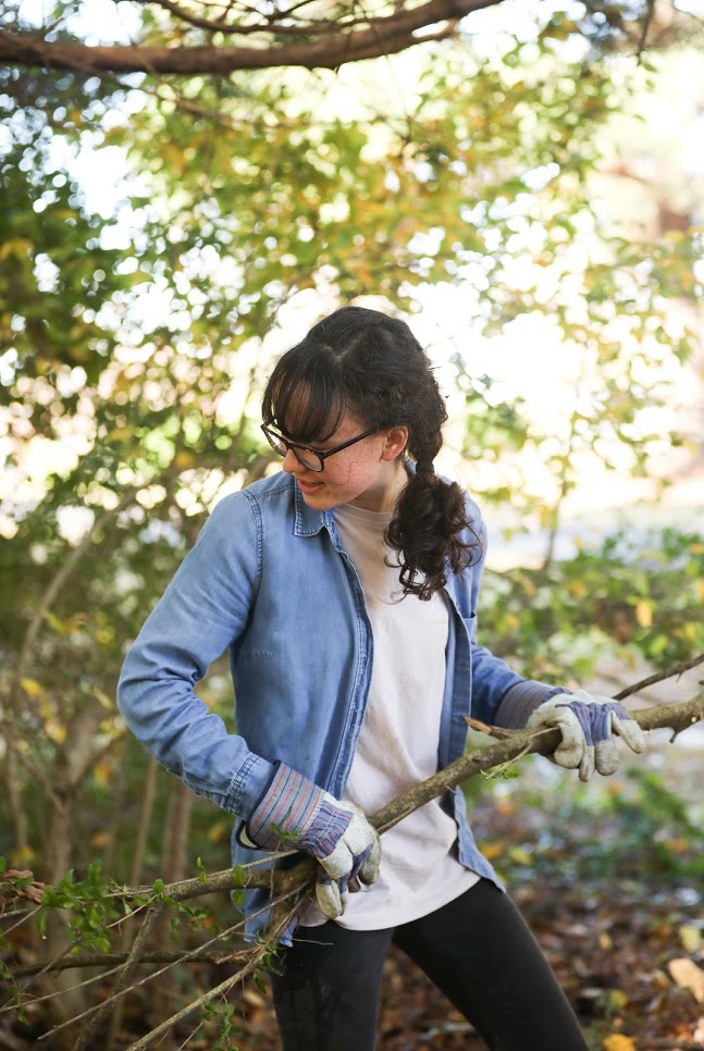 Lillie Salazar collects branches in the wooded area of Liberty Garden Park and Arboretum as part of the history department's community service project there on November 6, 2018. Photo by Kristi Woody