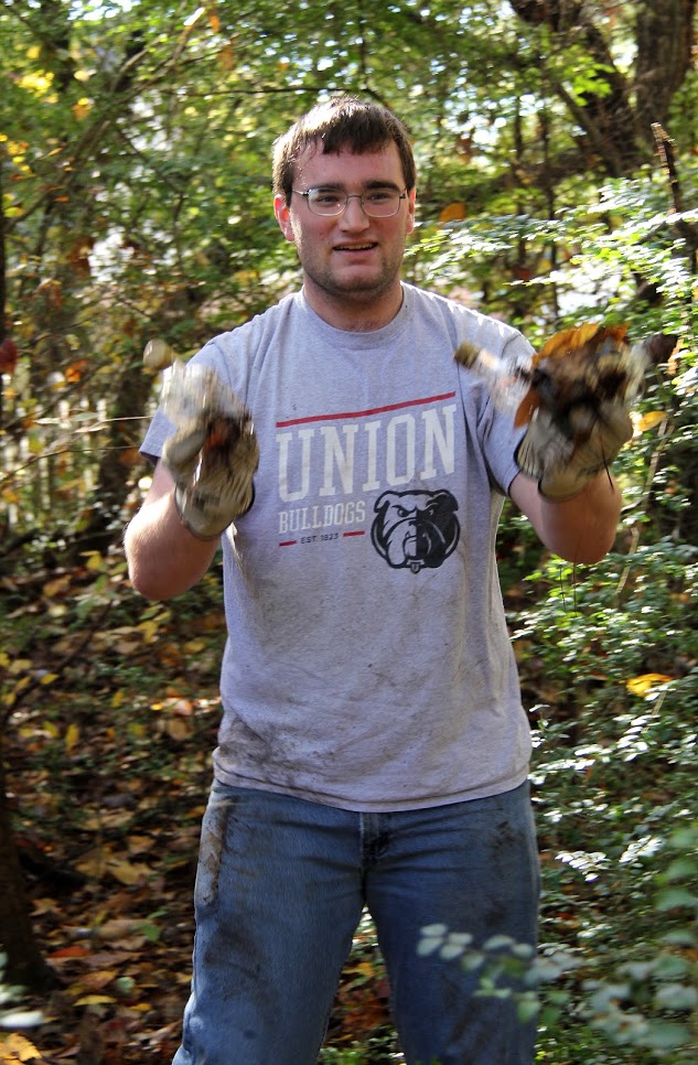 History club member Miles Randall shows off some of the litter he found in the wooded area of Liberty Garden Park during the history department's community service project there on November 6, 2018.
