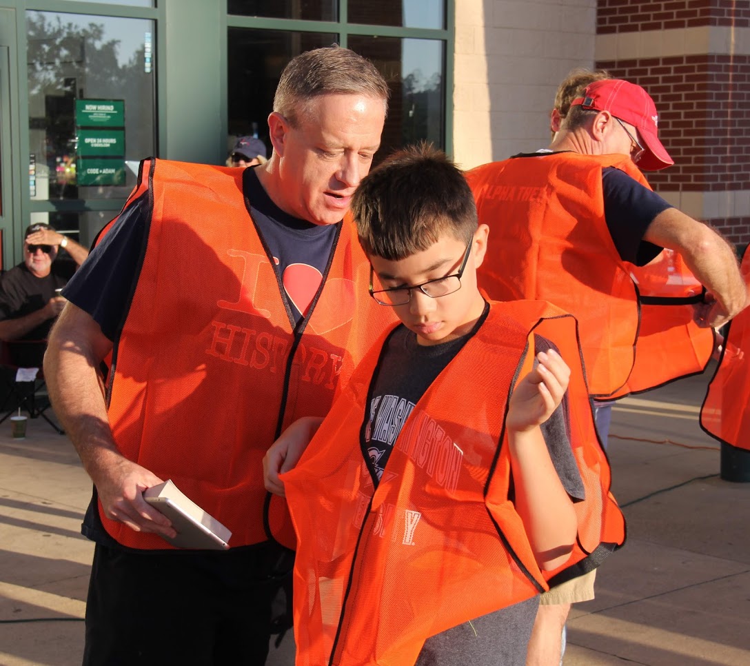 Dr. Henry Allen (left) helps his son Matthew straighten out his safety vest prior to the Racing So They Can Ride foot races on September 15, 2018.