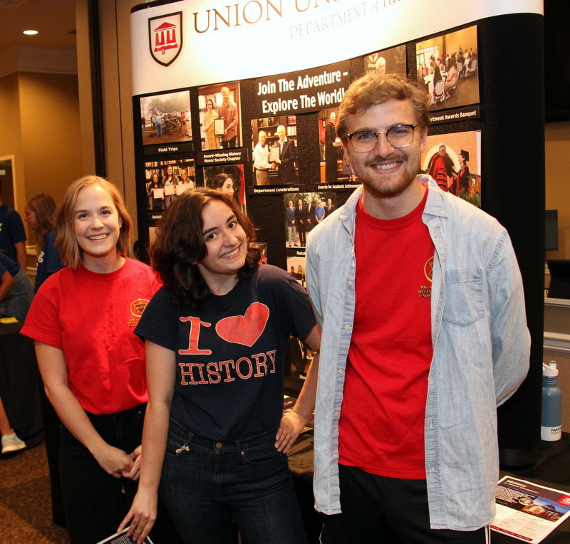 History student club leaders stand in front of the history department display table at the Campus Life Fair on August 18, 2019. They are (left to right) Phi Alpha Theta Vice President Megan Ledbetter, Rutledge Honorary History Club President Leah Atkins, and Phi Alpha Theta President Luke Sower.