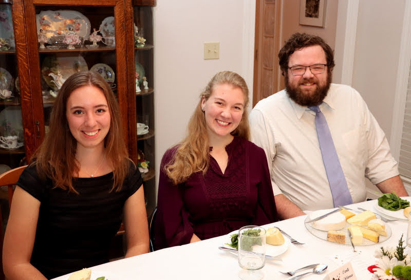 Emma Otto (left to right), Camille Wehrman, and Christopher Hearn smile for the camera at the Phi Alpha Theta French Christmas dinner on December 7, 2019.