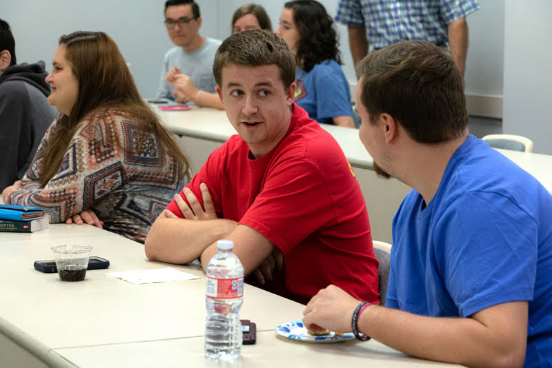Reagan Smith (wearing red T-shirt) talks to Macon Bullock prior to the Phi Alpha Theta initiation/plenary meeting on September 24, 2019. Sandra Allen is on the left. Photo by Joey Echeverria