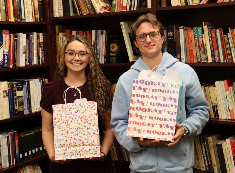 Phi Alpha Theta members Johnna Wade (graduating history major) and Joe Gee (graduating history minor) show off their history department awards sacks during a presentation ceremony on December 3, 2021.