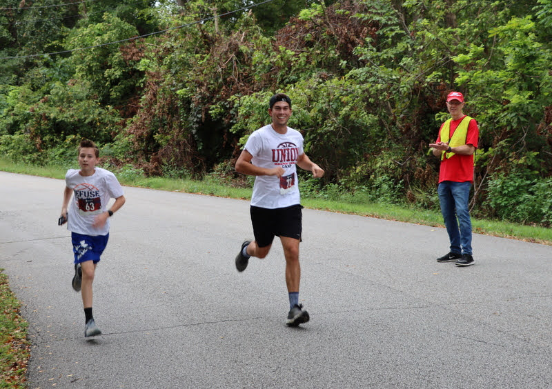 Phi Alpha Theta volunteer Robert Briley (right) cheers on runners in the Racing So They Can Ride races on September 18, 2021.