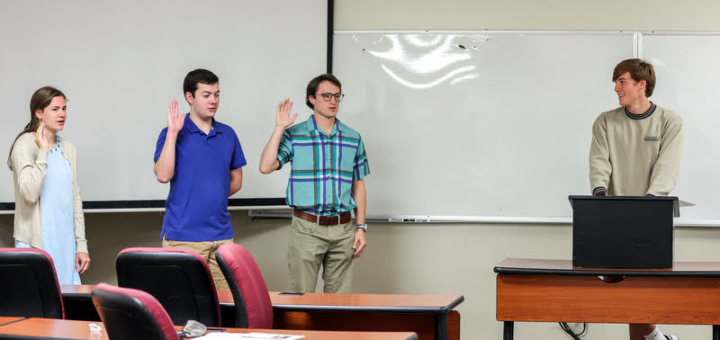 Delta-Psi Chapter Vice President Tad Binkley (right) leads the new initiates in the Phi Alpha Theta membership oath on September 27, 2021. The new inductees are (left to right) Anna Yadkowski, Jack Jenkins, and Joe Gee. Photo by Kristi Woody