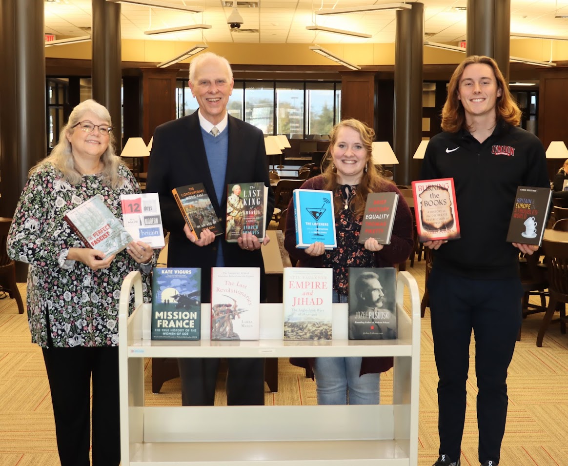 Phi Alpha Theta President Tad Binkley (right) and Vice President Breanna Edmiston (second from right) join Library Director Melissa Moore (left) and Phi Alpha Theta Faculty Advisor Dr. Stephen Carls (second from left) at a Delta-Psi chapter book presentation ceremony on November 16, 2022.